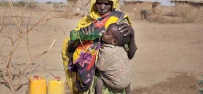 A mother gives her son a drink of water from an Oxfam tank in Ethiopia