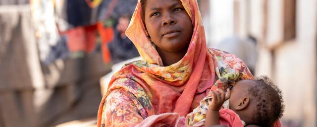 Shaima Ali, a refugee from Sudan in Renk, South Sudan speaks on her experience relocating after being displaced from the conflict in Sudan while holding her baby Fahima during feeding time.