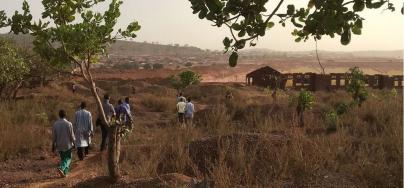Residents of Kintinian in northeastern Guinea walk past an open-pit oxide gold mine. Photo: Inclusive Development International