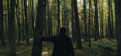 A woman standing in the middle of a forest, in cold temperatures.