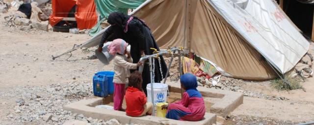 Une femme et des enfants prennent de l’eau potable à la rampe de distribution installée par Oxfam dans un camp pour personnes déplacées, à Huth. Photo : Kate Wiggans/Oxfam