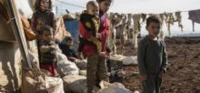 Children try to warm themselves in the sun outside their tent at an informal settlement for Syrian refugees in Lebanon's Bekaa Valley.