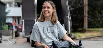 Anastassia* smiles in front of one of the specially equipped taxis her new business will soon provide people with disabilities in Mykolaiv city.
