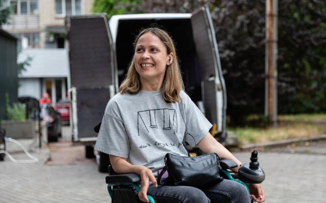 Anastassia* smiles in front of one of the specially equipped taxis her new business will soon provide people with disabilities in Mykolaiv city.