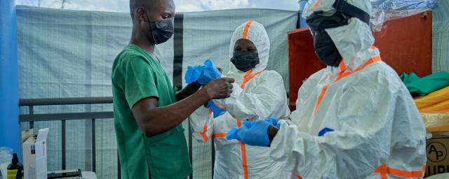 Joseph Kandule assisting team in protective suits with gloves.  Preparation of hygiene teams before entering the Ebola treatment area.