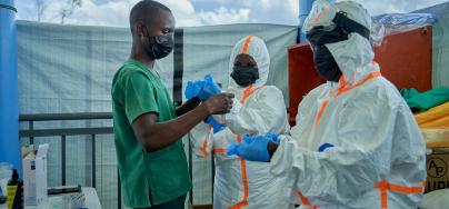 Joseph Kandule assisting team in protective suits with gloves.  Preparation of hygiene teams before entering the Ebola treatment area.